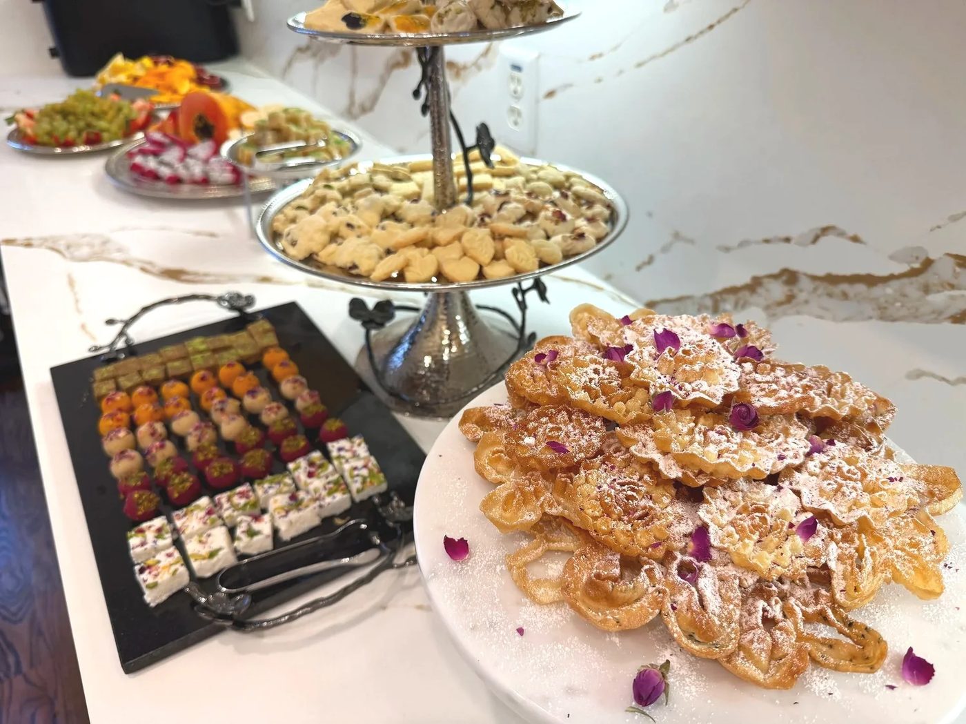 A full spread of Persian sweets on a tiered stand and platters