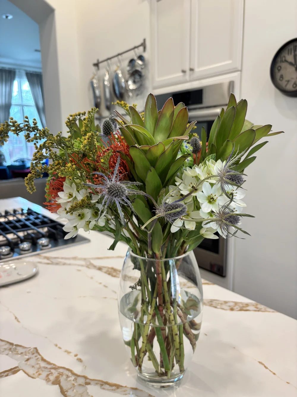 Protea, thistle and orange blooms in a kitchen bouquet
