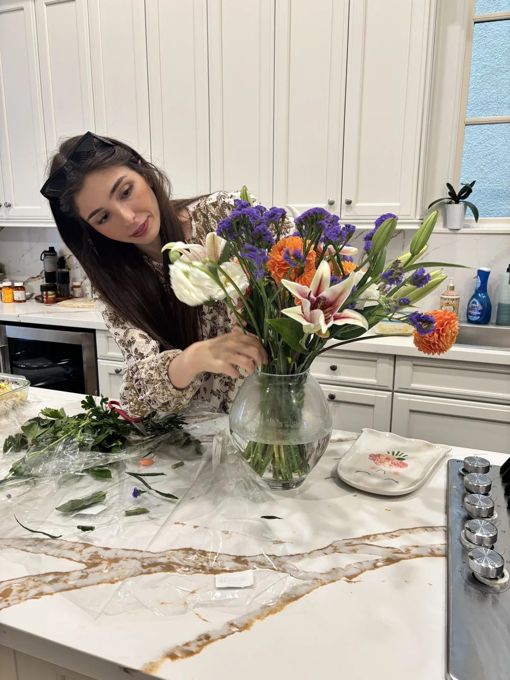 Arta arranging lilies and purple statice in the kitchen