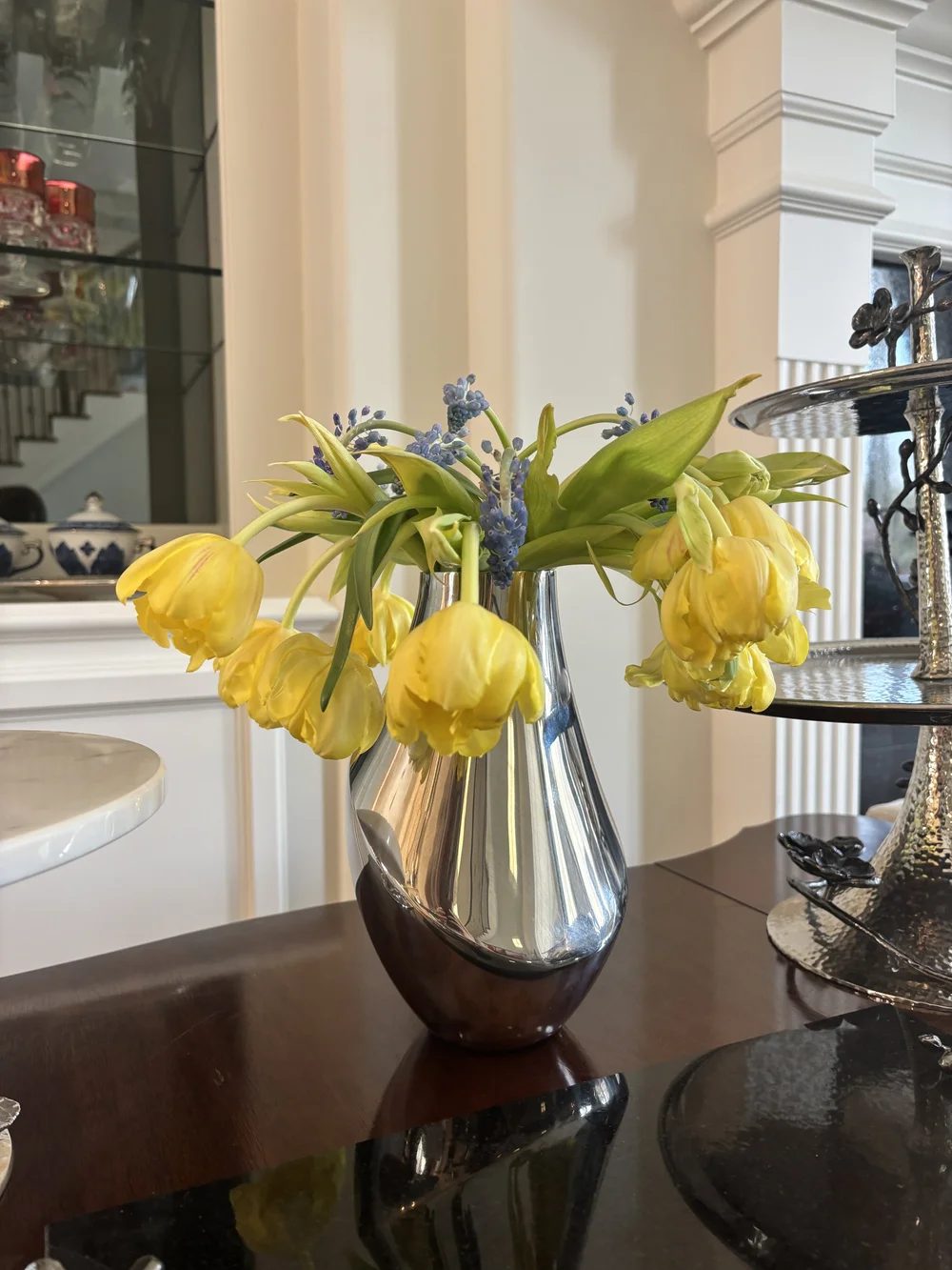 Yellow parrot tulips spilling from a silver pitcher