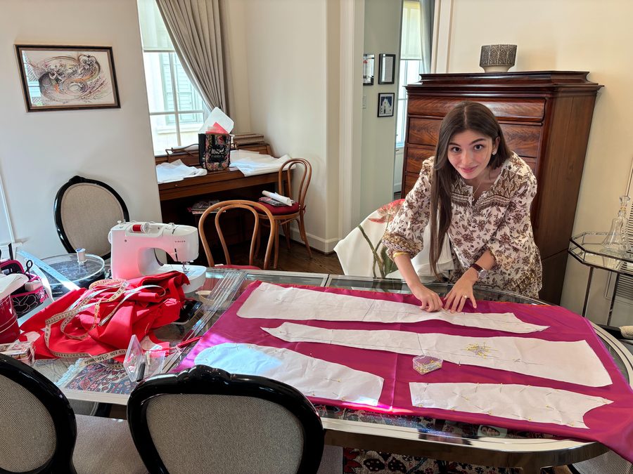 Arta laying out a bright pink dress pattern across a table