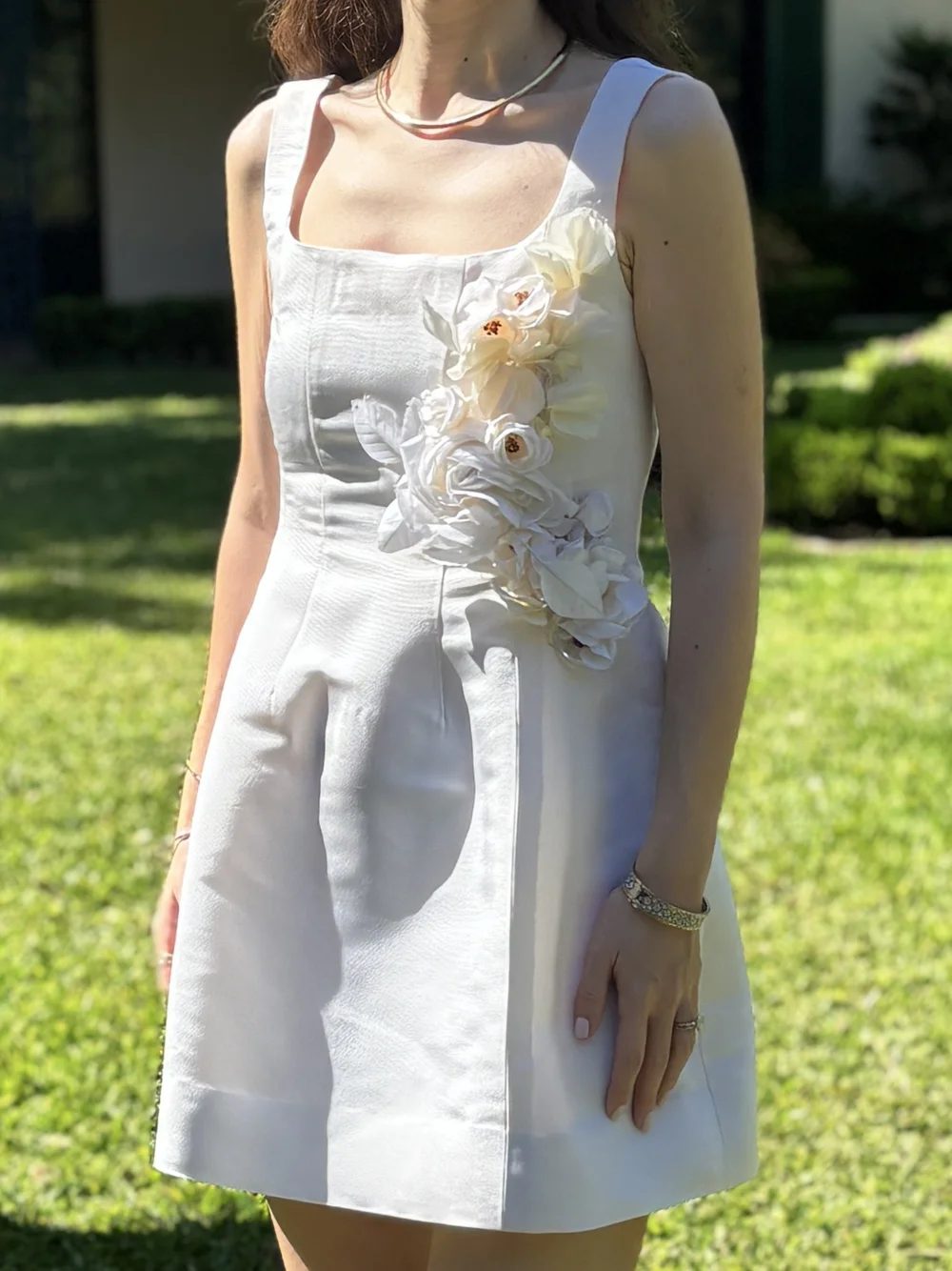 A white jumpsuit with a hand sewn fabric flower at the waist