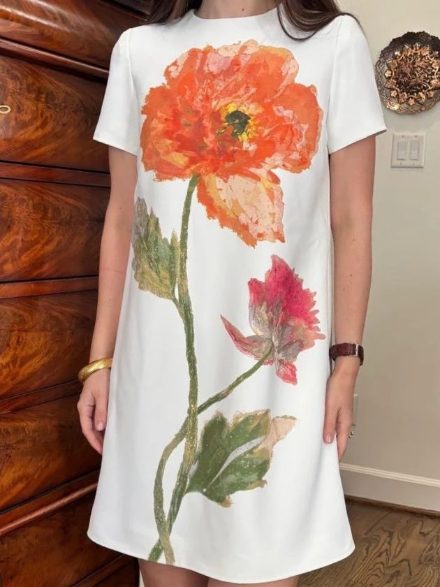 A white shift dress painted with a single orange poppy