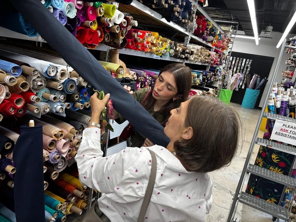 Arta and her mom choosing fabric from a wall of bolts