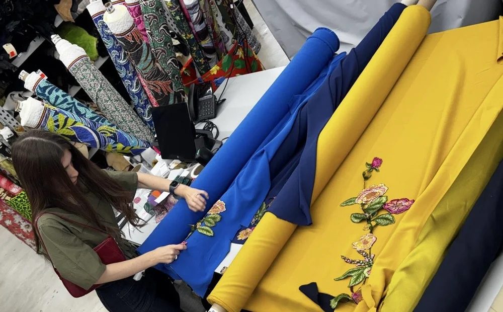 Cobalt and yellow embroidered fabrics laid out on a counter